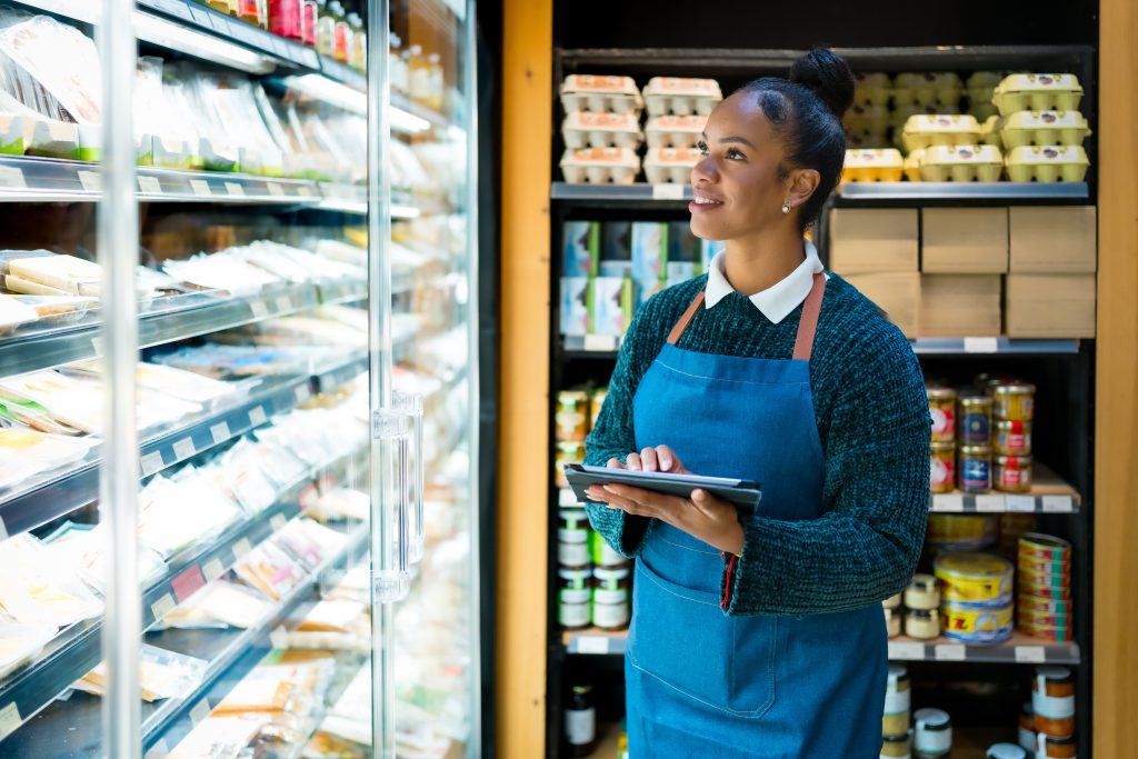 A grocery store employee taking stock of items on a shelf